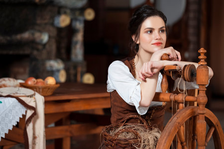 Portrait of Lovely Dreaming Caucasian Brunette Woman Posing With Spinning Wheel in Retro Dress In...