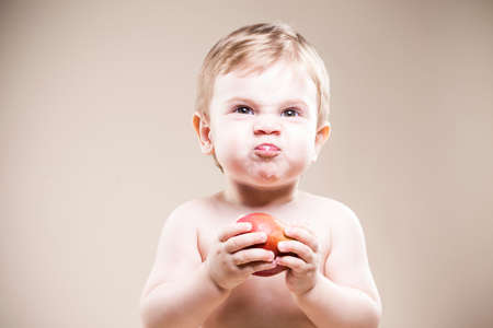 Portrait of Funny Little Boy With Food in Hands Posing Against Beige Background. Horizontal Shotの写真素材