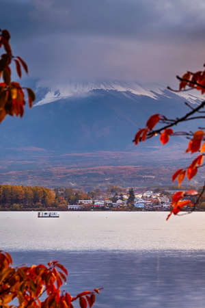 Kawaguchiko Lake in Front of Japanese Fuji Mountain with Bridge and Fishing Boats in Foreground During Red Maples Trees in Japan At Sunset. Vertical Image Orientationの写真素材