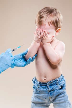 Portrait of Little Crying Caucasian Boy Is beeing Vaccinated with Protective Vaccine. Vertical Imageの写真素材