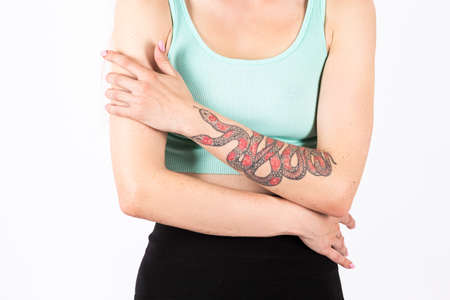 Closeup Image of Caucasian Female Hands With Artistic Snake Tattoo Posing Against White. Horizontal Image Compositionの写真素材