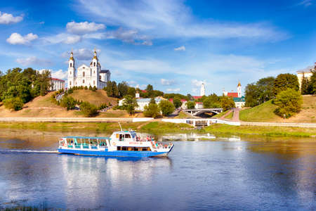 Vitebsk, Belarus - 1 August, 2021: Traditional River Cruises Across the Dvina River in Vitebsk with The Holy Assumption Cathedral and Resurrection Church on Background in Vitebsk, 1 August, 2021のeditorial素材