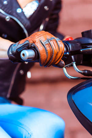 Closeup of Hands of Female Biker In Leather Protective Gloves and Black Jacket Holding Accelerator Handle of Motorbike.Vertical imageの写真素材
