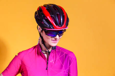 Portrait of Positive Female Road Cyclist in Professional Sport Outfit Posing Against Yellow Background. Horizontal Image Compositionの写真素材