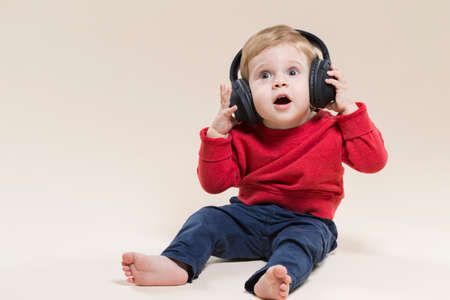 Portrait of Little Caucasian Child Posing With Headphones While Sitting Against Beige Background. Horizontal Image Compositionの写真素材