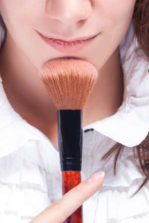 Makeup Concepts. Closeup of Face of Beautiful Caucasian Young Woman Posing with Make-up Brush Near Face with Smile. Vertical Shotの写真素材