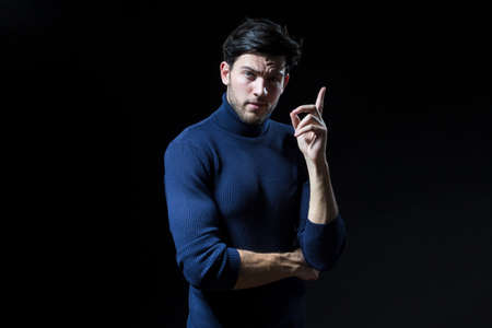 Portrait of Caucasian Handsome Brunet Man Posing in Blue Turtle Neck Sweater With Folded Hands Against Grey Background With Copy Space as Successful Young Man.Horizontal Imageの写真素材