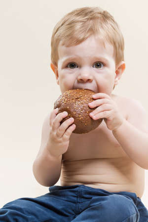 Closeup Portrait of Little Caucasian Child With Red Apple Fruit in Hands While Eating And Posing Against Beige Background. Horizontal Imageの写真素材