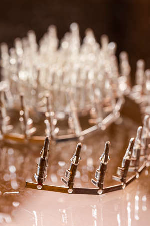 Line of Silver Tinned External PCB Angular Connectors Over Reflective Surface. Vertical  Image...