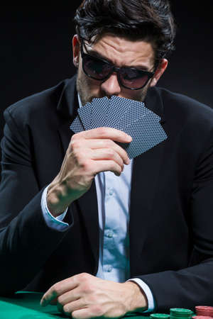 Casino Concepts. Serious Caucasian Young Handsome Pocker Player With Bunch of Cards At Face At...