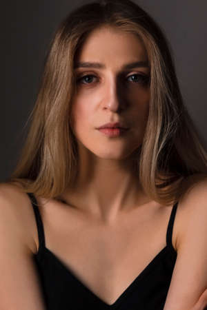 Portrait of Passionate Caucasian Blond Girl With Long Beautiful Hair Posing Against Dark Background. Vertical Compositionの写真素材