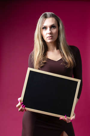Young Caucasian Blind Woman Holding Posing With Empty Black Chalkboard Against Crimson Background. Vertical Imageの写真素材