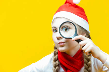 Portrait of Young Caucasian Excited Girl Posing in COlorful Knitted Winter Scarf and Warm Hat Posing with Lifted Hands Over Yellow Background. Horizontal Imageの写真素材