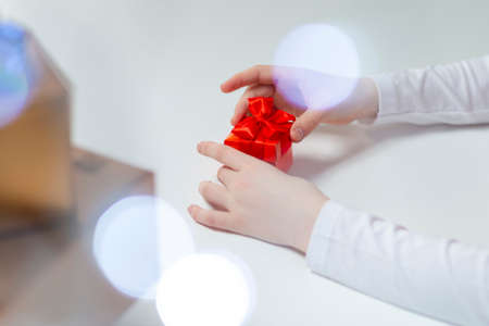 Hands of Caucasian Female Holding Red Gift Box Along with Batch of Wrapped Present Boxes on Side.Horizontal Shotの写真素材