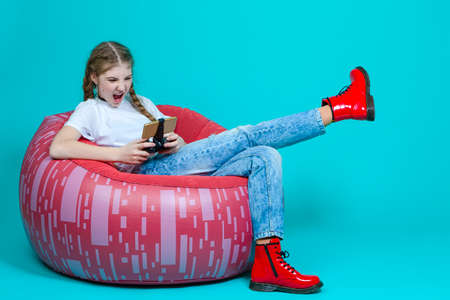 Little Guitar Player With Yellow Bass Guitar Posing While Standing In Fashionable Red Jacket Over Trendy Turquoise Background. Vertical image Orientationの写真素材