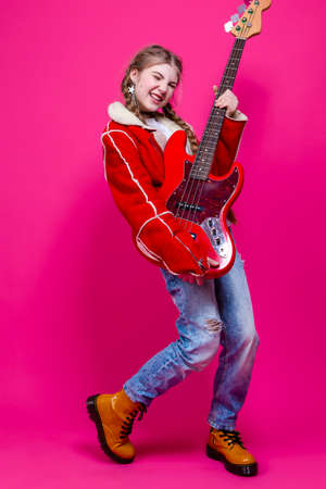 Winsome Caucasian Female Guitar Player With Yellow Bass Guitar Posing In Fashionable Yellow Hoody...