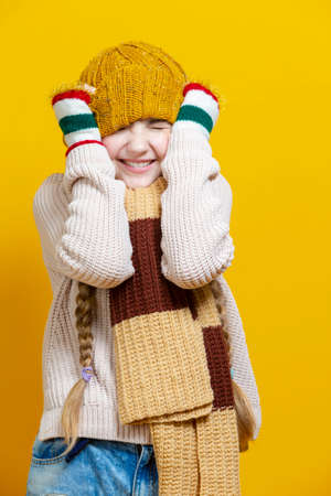 Playful Funny Caucasian Teenage Girl in Striped Shirt Holding Yellow Bottle of Sun Protection Gel Cream While Squeezing Over Yellow Background. Vertical Imageの写真素材