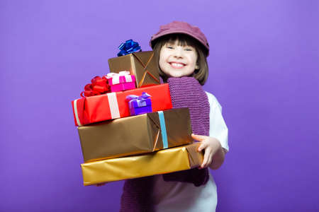 Laughing Little Caucasian Girl Kid in Cap Hat and Knitted Scarf Posing with Big Pile of Wrapped...