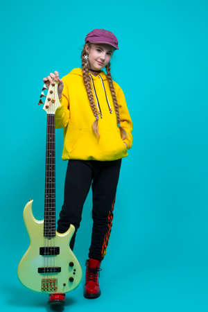 Playful Funny Caucasian Teenage Girl in Striped Shirt Holding Yellow Bottle of Sun Protection Gel Cream While Squeezing Over Yellow Background. Vertical Imageの写真素材