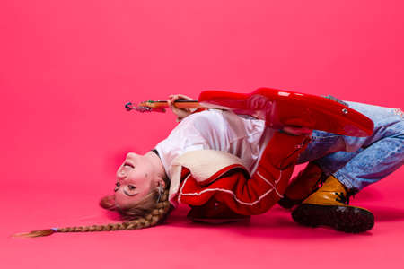 Expressive Caucasian Teenage Guitar Player With Red Polished Bass Guitar Posing In Fashionable Red...