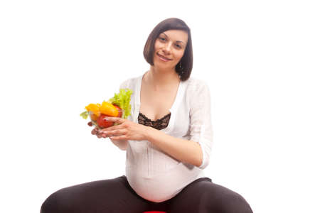 Portrait of Caucasian Brunette Woman in White Shirt Sitting on Big Fitball While Holding Bowl With...