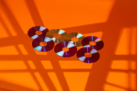 Variety of Arranged CD Disks or DVD Disks on Orange Background With Different Rectangular Rays...