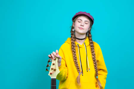 One Winsome Caucasian Blond Girl In Warm Knitted Sweater Posing with Glasses and Lifted Hand While Thinking And Touching Shoulder Against Yellow. Horizontal Image Compositionの写真素材