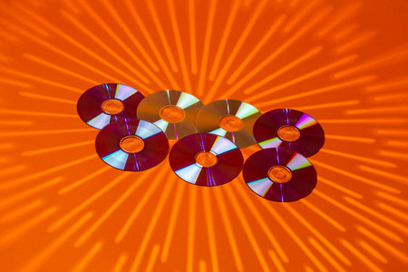 Variety of Arranged CD Disks or DVD Disks on Orange Background With Different Circular Rays Patterns...