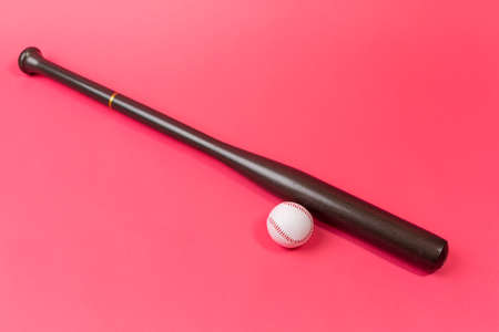 Image of Stylish Laquered Wooden Brown American Baseball Bat Placed With Clean Leather White Baseball Ball Together Over Trendy Coral Pink Background. Horizontal Imageの写真素材