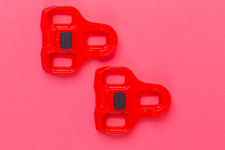 Pair of New Red Cycling Cleats Over Pink Coral Background.Horizontal Shot