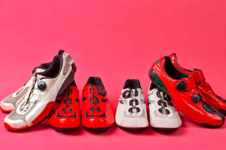Four Pairs of Carbon Red and White Professional Cycling Shoes Placed Together in Line Over Pink...