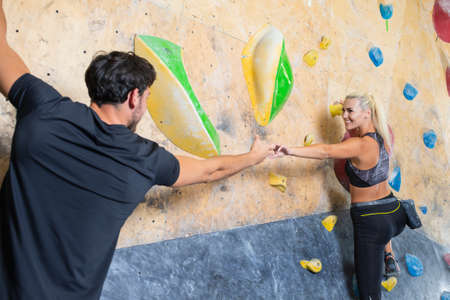 Couple of Caucasian Athletes Climbing Up Together on Steep Rock climbing on artificial wall indoors...