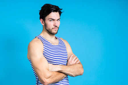 Serious Handsome Brunet Man in Striped Underware During Early Morning Posing With Hands Folded In Front Against Seamless Blue Background.Horizontal Compositionの写真素材