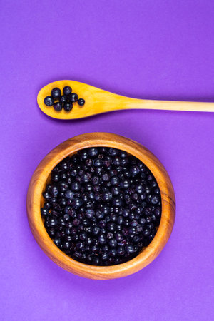 Food Concepts. Variety of Fresh Forest Blueberries Placed in Wooden Bowl With Spoon Over Purple Background. Vertical image Compositionの写真素材