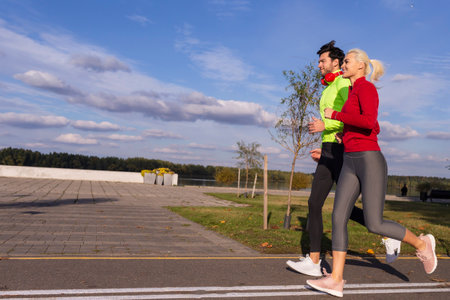 Couple Jogging Outside as Runners Training Outdoor Working Out While Wearing Headphones in City As...