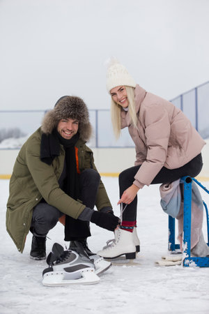 Young Caucasian Couple in Winter With Ice Skates Posing Together Over a Snowy Winter Landscape Outdoor. Vertical Orientationの写真素材