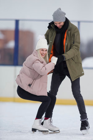 Youth Lifestyle. Young Caucasian Couple in Winter With Ice Skates Posing Together Over a Snowy Winter Landscape Outdoor. Vertical imageの写真素材