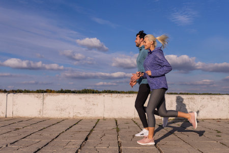 City Running Couple Having Jogging Outside as Runners During Training Outdoor Working Out Happily Smiling While Having Fitness Exercise. Horizontal Imageの写真素材