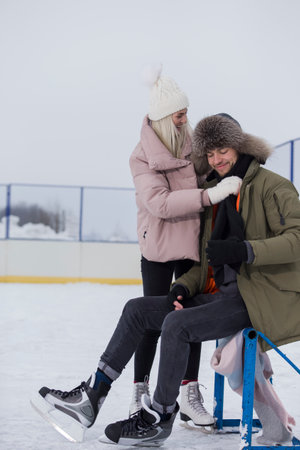 Sports and Lifestyle. Young Caucasian Couple in Winter With Ice Skates Posing Together Over a Snowy Winter Landscape Outdoor. Vertical Imageの写真素材