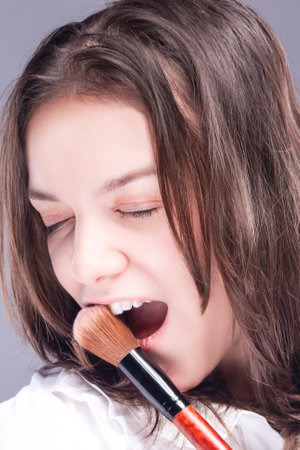 Portrait of Smiling Winsome Caucasian Makeup Artist Woman with Brushes Posing With Smile Over Gray. Vertical imageの写真素材