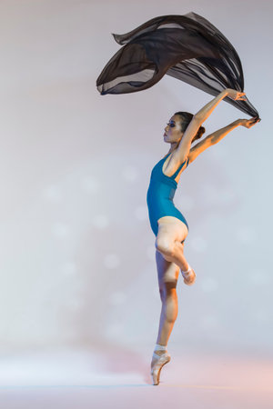Professional Japanese Female Ballet Dancer Posing in Pale and Blue Dress With Flying Black Cloth In Hands Against White Background. Vertical Shotの写真素材