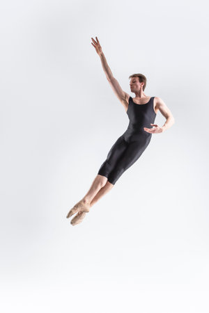 Caucasian Ballet Dancer Young Caucasian Athletic Man in Black Suit Posing Flying Dancing in Studio On White. Vertical image Compositionの写真素材