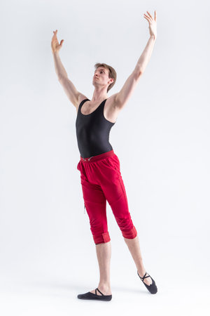 Stretching of Concentrated Contemporary Ballet Dancer Flexible Athletic Man Posing in Red Tights in Ballanced Dance Pose on White.Vertical Shotの写真素材