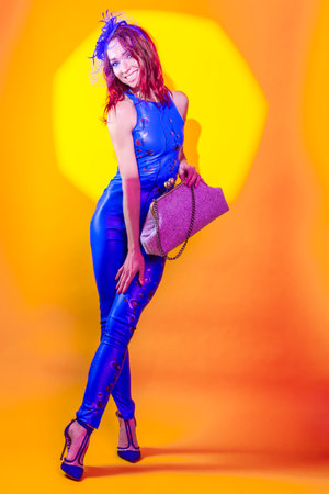 Happy Blond Woman in Blue Artistic Dance Suit Posing In Shawl Hat With Hand Made Hand-Bag With Octagon Shaped Light On Yellow Background. Vertical Image Orientationの写真素材