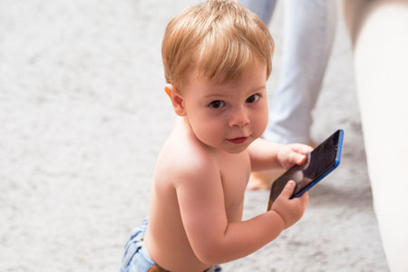 One Positive Caucasian Child Posing With Cellphone Indoors While Looking Backwards. Horizontal Shotの写真素材