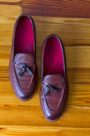 Pair of Wonderful Traditional Formal Stylish Brown Pebble Grain Tassel Loafer Shoes On Wooden Surface. Vertical orientationの写真素材