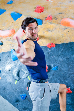 Professional Male Rock climber man hanging on a bouldering climbing wall With Outstretched Hand...