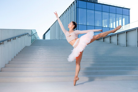 Graceful Sexy Slim Professional Caucasian Ballet Dancer in Rose Pink Tutu Dreass Whie Posing In Dance Flying Pose Against Blue Stairs  In Stretched Pose Outdoor. Horizontal Image Orientationの写真素材