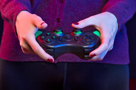 Cool Caucasian Girl in Trendy Violet Jacket Holding Black Button Joystick Standing Against Dark...
