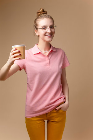 One Winsome Beautiful Caucasian Girl In Pink Shirt With Paper Disposable Cup Posing WIth Drink...